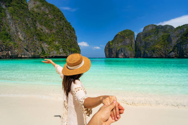 young couple traveler relaxing and enjoying at beautiful tropical white sand beach at maya bay in krabi, thailand, summer vacation and travel concept - phi phi islands imagens e fotografias de stock