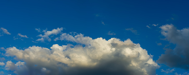 Cumulus clouds with dark gray clouds on a blue sky. Web banner.