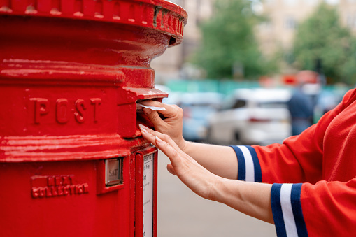 A  black  rural mailbox with the flag raised and copy space on blank  envelopes in the mailbox. Isolated on a white background.