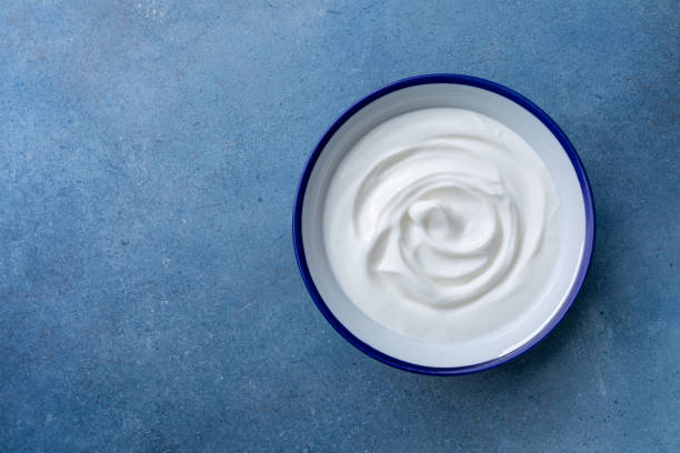 istock Greek yogurt in bowl on blue stone table top view. 1404138851