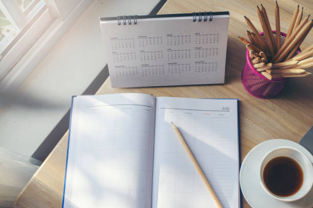 istock Diary, Calendar and agenda for Event Planner to plan timetable, appointment, organization, management on office table. Desktop Calender and coffee place on wooden desk. Calendar Background Concept 1404139522