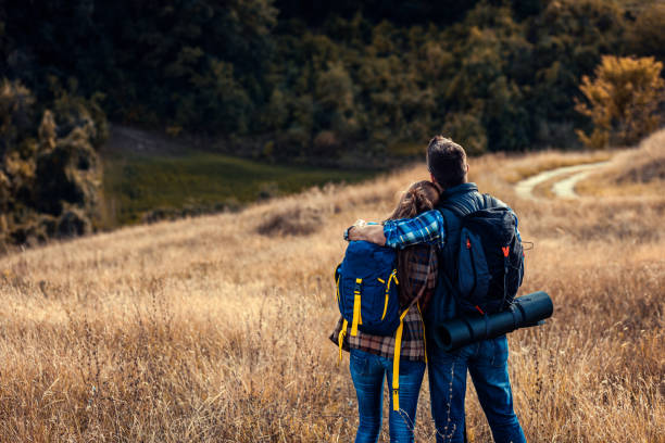 istock Couple with backpacks hiking together on countryside during sunset. 1404141075