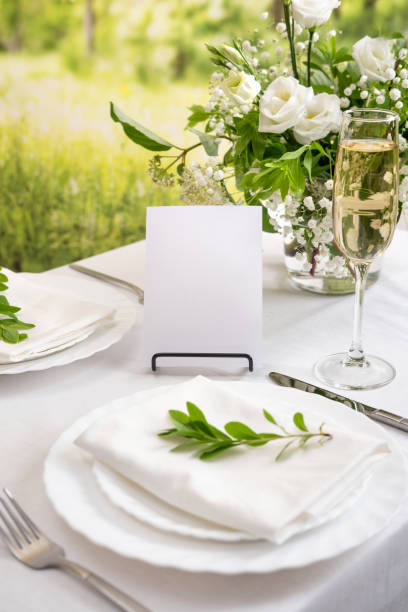 istock Mockup white blank space card for table number or menu. Wedding teble decoration with white flowers, glasses and white napkins. Elegantly decorated table at a wedding reception. Festive table setting. The wedding decor. 1404145138