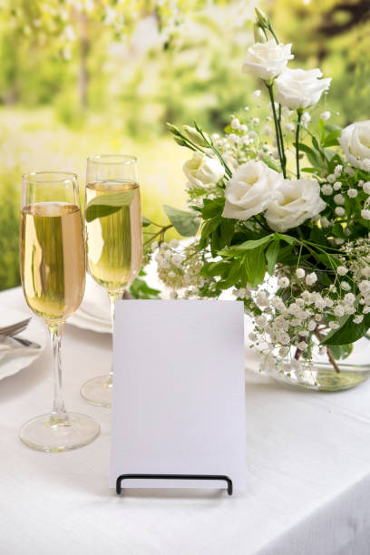 istock Mockup white blank space card for table number or menu. Wedding teble decoration with white flowers, glasses and white napkins. Elegantly decorated table at a wedding reception. Festive table setting. The wedding decor. 1404145157