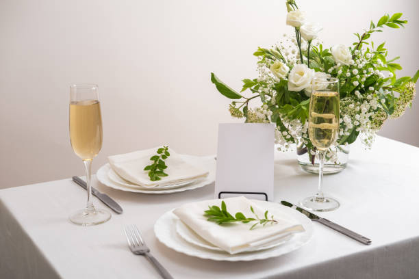 istock Mockup white blank space card for table number or menu. Wedding teble decoration with white flowers, glasses and white napkins. Elegantly decorated table at a wedding reception. Festive table setting. The wedding decor. 1404145169