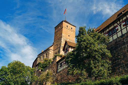 Old medieval tower with German flag in the historical part of the city on a sunny day,  castle of nuremberg\nNuremberg, Bavaria, Germany
