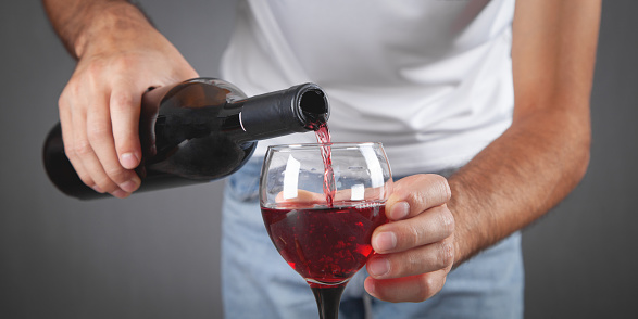 Pouring red wine into the glass.