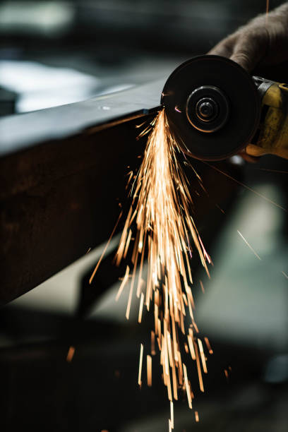 Close up of cutting metal with electric saw. Close up of unrecognizable worker cutting iron with hand saw in a workshop. steel grinding stock pictures, royalty-free photos & images