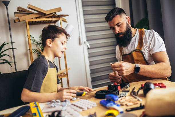 istock Father teaches his son to plan wood in a carpentry workshop. Hobby and education concept 1404150726
