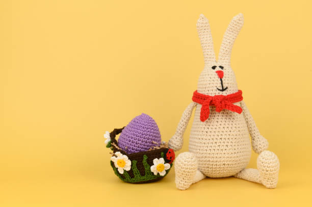 istock Knitted Easter Bunny in a red scarf with a basket and a yellow egg in it 1404151558