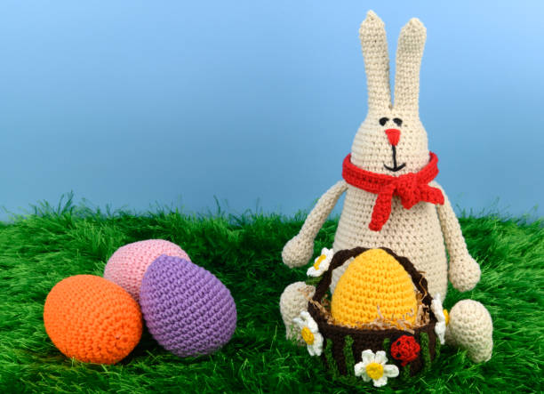 istock Knitted Easter Bunny in a red scarf with a basket and a yellow egg in it 1404151654