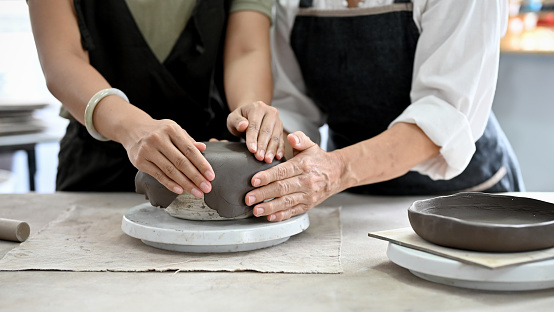 Cropped image, Hands making a clay pottery, moulding a clay pottery in the workshop. Handcraft, Handmade kitchen cookware.