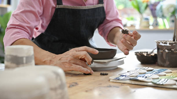 istock Cropped image, Aged woman decorating her clay pot at her handicraft table. 1404154311