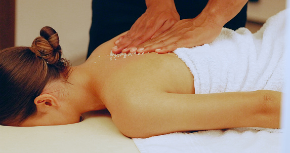 Woman having a massage at a spa. A young woman enjoying a relaxing day of beauty and wellness at a luxury health spa while a therapist rubs her back