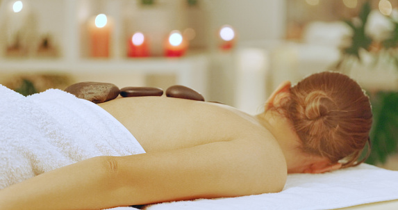 Woman having a hot stone massage at a spa. A young woman enjoying a relaxing day of beauty and wellness at a luxury health spa with lastone therapy