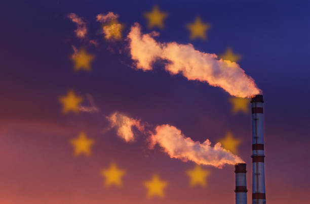 на фоне флага евросоюза дым идет из дымоходов предприятия. - factory night skyline sky стоковые фото и изображения