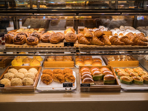 Assorted pastry and bread arranged on tray selling at bakery shop.