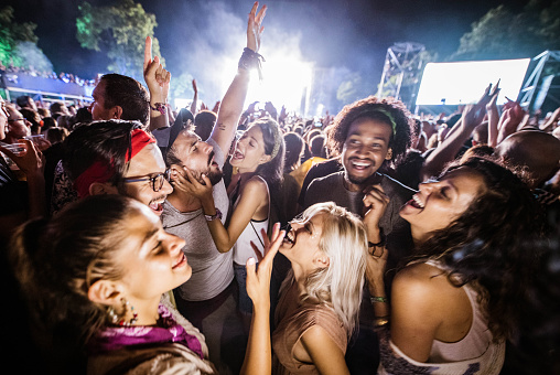 Large group of cheerful people having fun on a music concert by night.