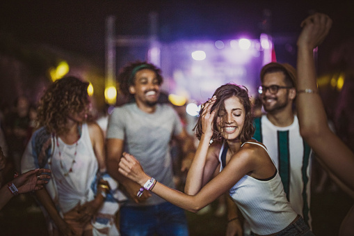 Large group of cheerful people having fun while dancing on music concert by night.