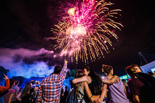 Rear view of crowd of people watching fireworks at night.