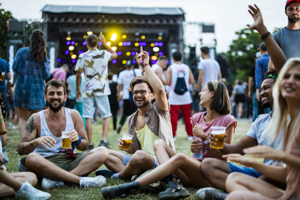 junge freunde entspannen auf gras während des musikfestivals. - freiluftkonzert stock-fotos und bilder