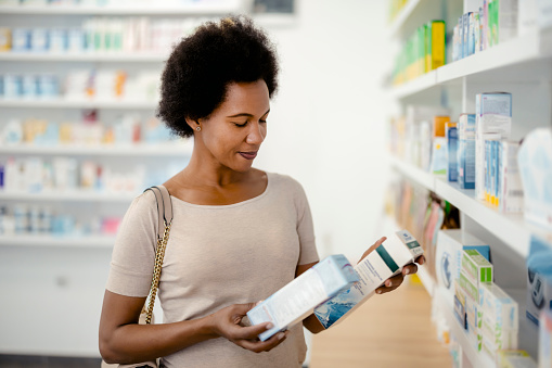 Pharmacy Drugstore: African American Female Customer Examining Medicament in Drug Store