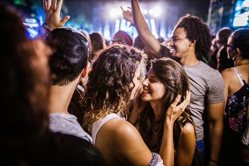 Young happy lesbians having fun during music concert by night.