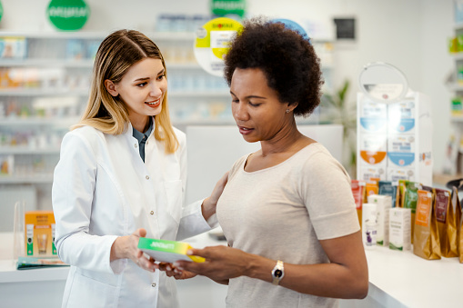 Female Pharmacist Helping Mature Black Woman Customer in the Pharmacy as She Explains a Prescription. Medicine Recommendation, Advice, Talking. Drugstore With Full of Drugs, Pills, Health Care