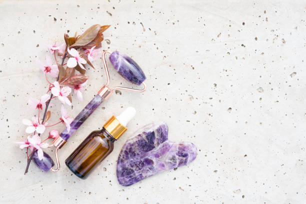 Flat lay composition with facial massage kit - amethyst gua sha tool and face roller with beauty face serum or cosmetic oil on stone concrete background with copy space. Mockup image, skin care concept composición plana con kit de masaje facial - herramienta de amatista gua sha y rodillo facial con suero facial de belleza o aceite cosmético sobre fondo de hormigón de piedra con espacio de copia. imagen de maqueta, concepto de cuidado de la piel