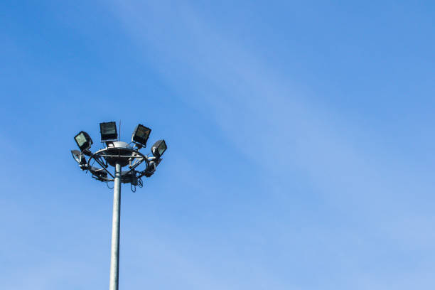 istock Spotlight on a high mast in the sky with clouds and protective mesh 1404158279