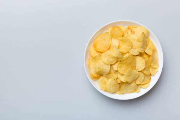 istock Potato chips on bowl isolated on colored background. Delicious crispy potato chips in bowl. Space for text. Top view 1404159889