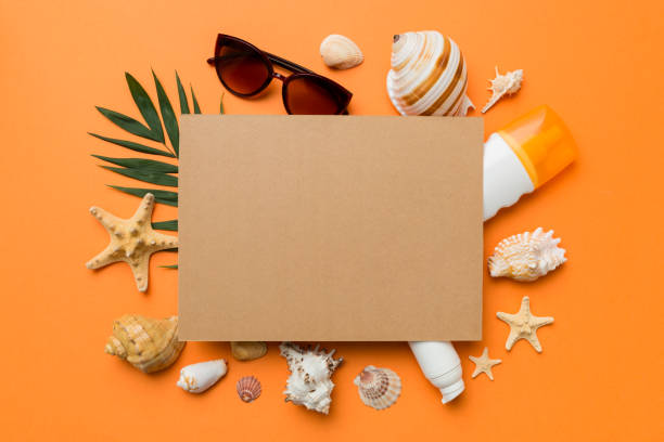 istock Summer time concept with blank greeting card and blank craft paper on colored background. Seashells from ocean shore in the shape of frame separated with space for text top view 1404160283