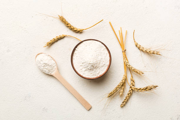 Flat lay of Wheat flour in wooden bowl with wheat spikelets on colored background. world wheat crisis stock photo