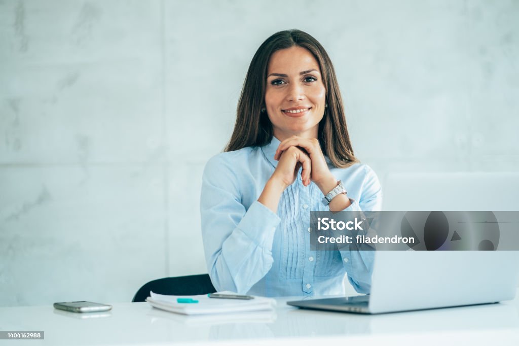 Portrait of confident businesswoman at workplace Smiling woman employee sitting behind laptop and looking at camera. Staff at work. Bank Manager Stock Photo