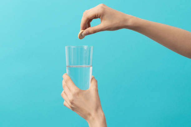 istock a female hand drops an effervescent tablet 1404167248