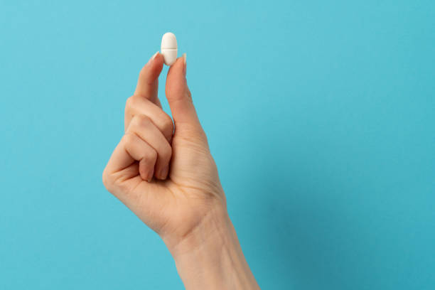 istock a female hand holding a single pill 1404168290