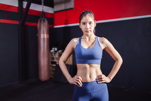 Portrait of a beautiful Asian woman standing in gym. Trainer or instructor fitness coach concept