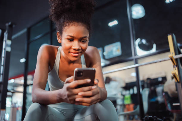 istock African-American woman using a smartphone during break time after workout at gym. 1404168496