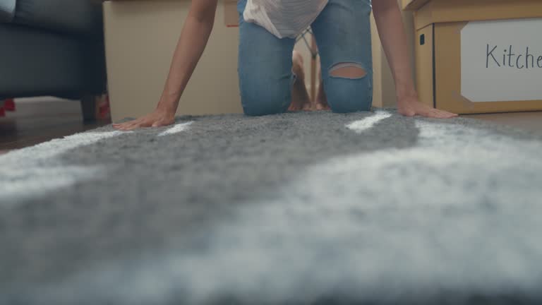 Close up of young Asian woman rolling carpet out and moving to new house.