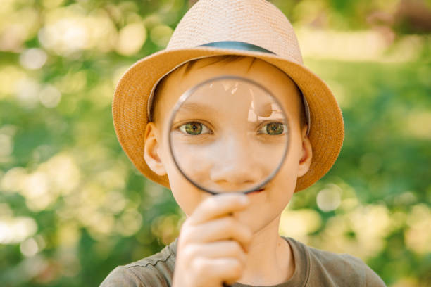 istock Caucasian Boy kid exploring nature environment with a magnifying glass loupe 1404173548