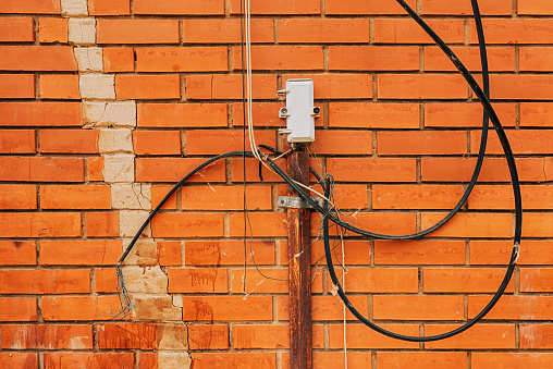 External outdoor telephone connection junction box with messy wires and cables on brick wall