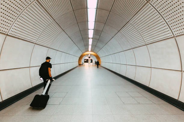Blurred motion of a commuter walking in a tunnel at Tottenham Court Road underground station, surrounded by the modern futuristic architecture of the new Elizabeth line development.