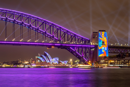 2022-06-18 - Milsons Point, NSW, Australia. This photo shows the Sydney Opera House and Harbour Bridge during the 2022 Vivid Sydney Festival. It is the first week of the event, after being cancelled for 2 years.