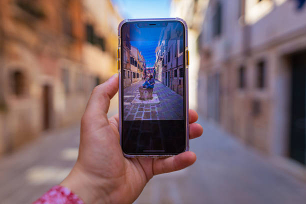 Close up phone screen in hand of white male tourist taking a photo of his girlfriend.