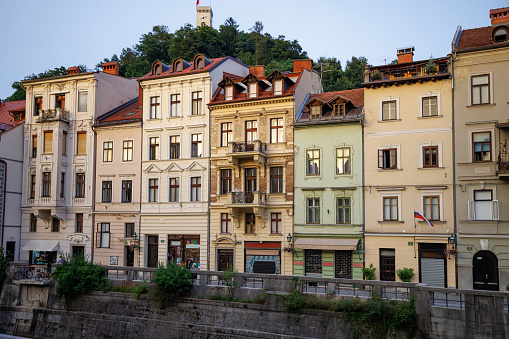 Stone embankment with a row of old fashioned buildings and shops in historical part of Ljubljana
