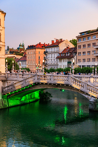 Beautiful illuminated stone bridge with railing over the river Ljubljanica in historical part of Ljubljana, tourist sightseeing area
