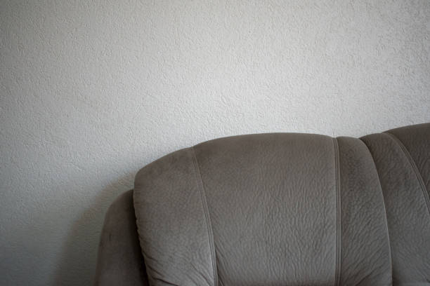 Gray soft sofa on a white wall background. Minimalist interior. Space for inscription. Quality image for your project