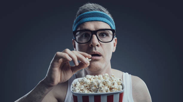 istock Funny guy watching movies and eating popcorn 1404178373