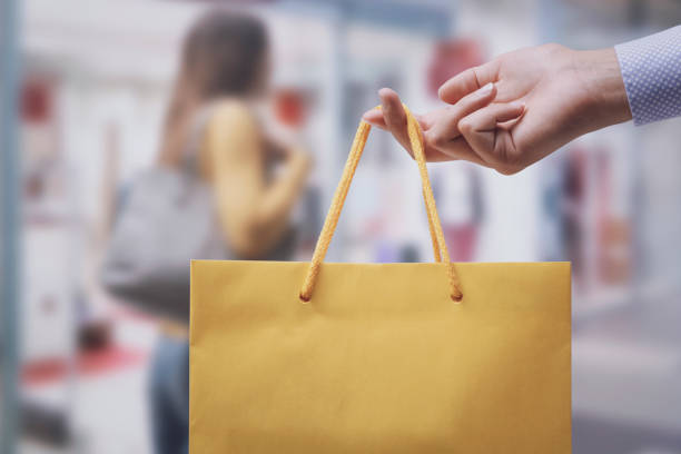 Woman holding a shopping bag and stores in the background