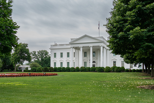 Front View of the White House and Green Grass With Cloudy Skies